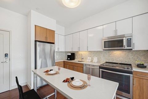 a kitchen with stainless steel appliances and a white table at The Merc, Waltham, MA, 02453